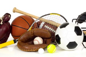 Variety of sports equipment on white background with copy space, items inlcude boxing gloves, a basketball, a soccer ball, a football, a baseball bat, a catcher's mitt or glove, a tennis racket and ball, a golf ball, and a baseball catchers mask