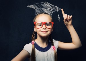 Genius girl in red glasses near blackboard in master hat